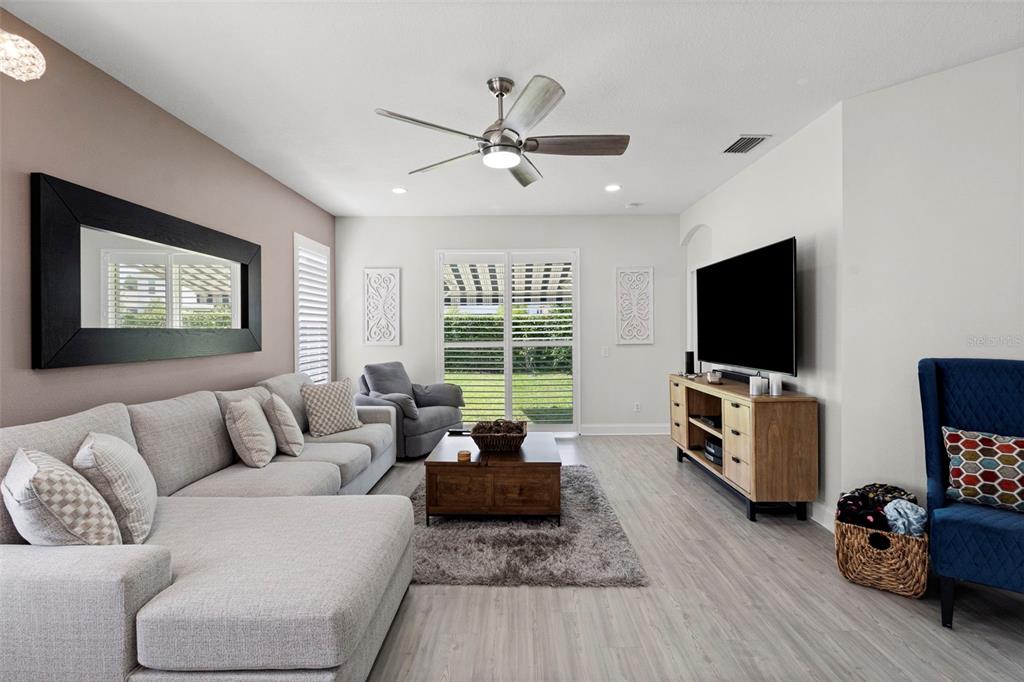 A living room features a grey sectional sofa, a wooden coffee table, and a television — 10818 ASHFORD OAKS DRIVE, TAMPA, FL