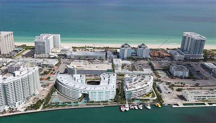 An aerial view shows high-rise buildings and a curved residential complex along a coastal waterfront — 6620 Indian Creek Dr # 607, Miami FL 33141, MIAMI, FL