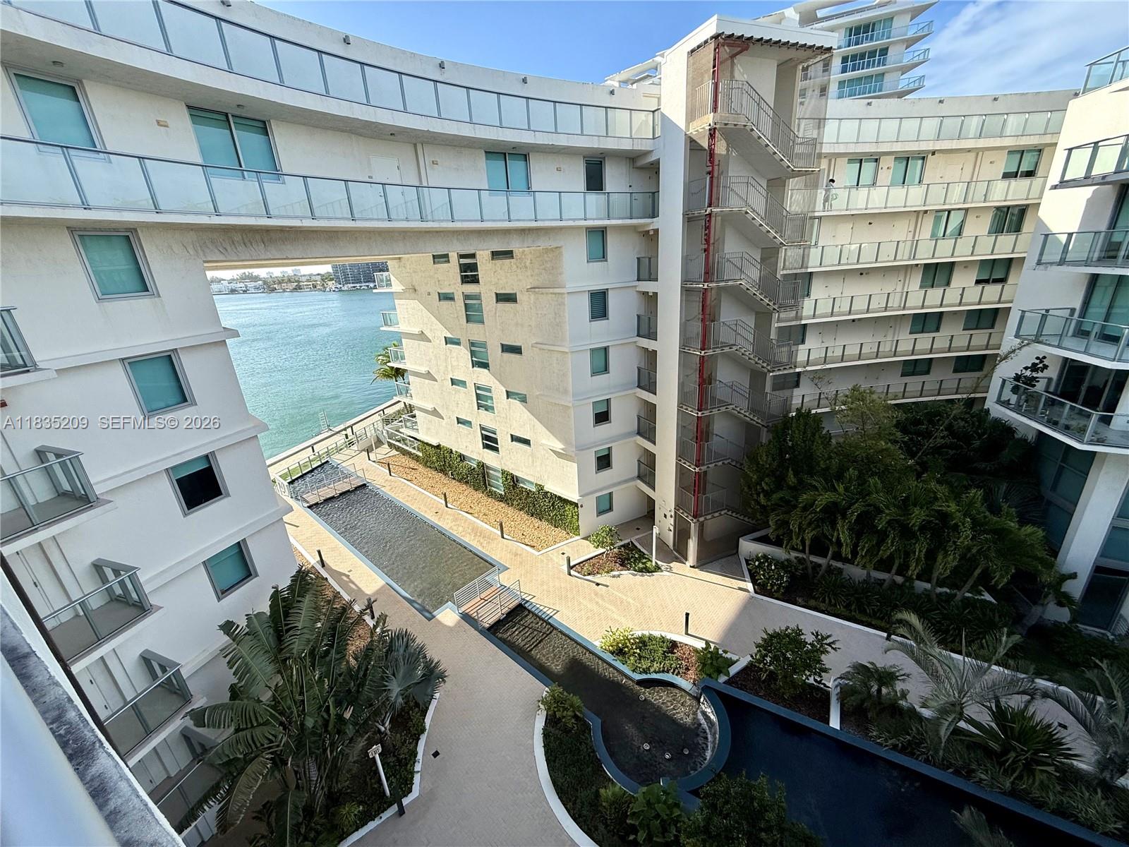 An elevated view of a modern apartment complex courtyard featuring a pool and waterfront access — 6620 Indian Creek Dr # 607, Miami FL 33141, MIAMI, FL