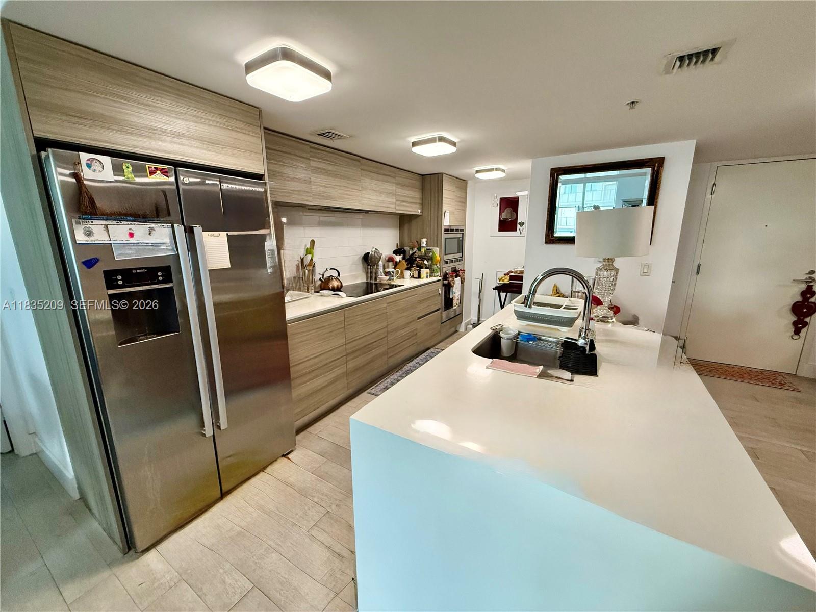 A modern kitchen features light wood cabinetry, stainless steel appliances, and a white quartz island — 6620 Indian Creek Dr # 607, Miami FL 33141, MIAMI, FL