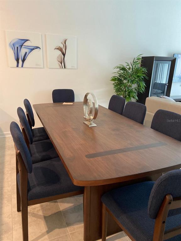 A dining room features a wooden table with blue chairs and two floral wall prints — 8863 CABOT CLIFFS DRIVE UNIT 102, DAVENPORT, FL
