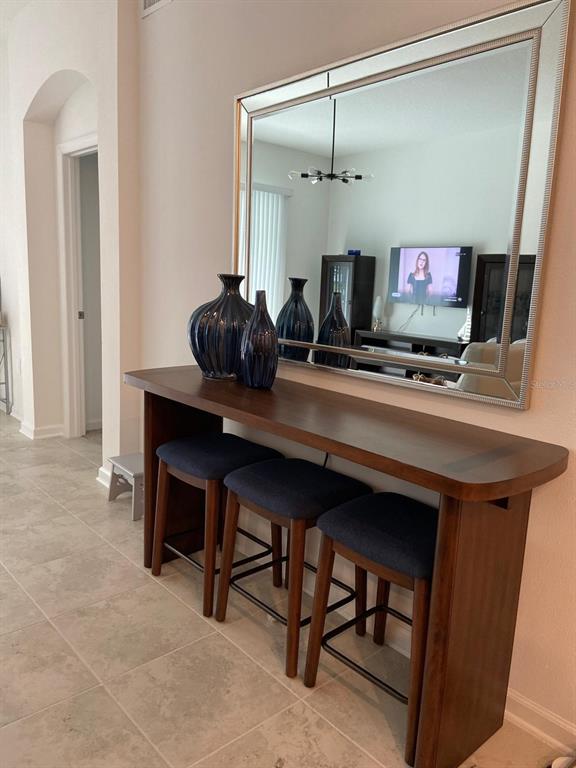 A wooden console table with three stools sits beneath a large mirror in a hallway — 8863 CABOT CLIFFS DRIVE UNIT 102, DAVENPORT, FL