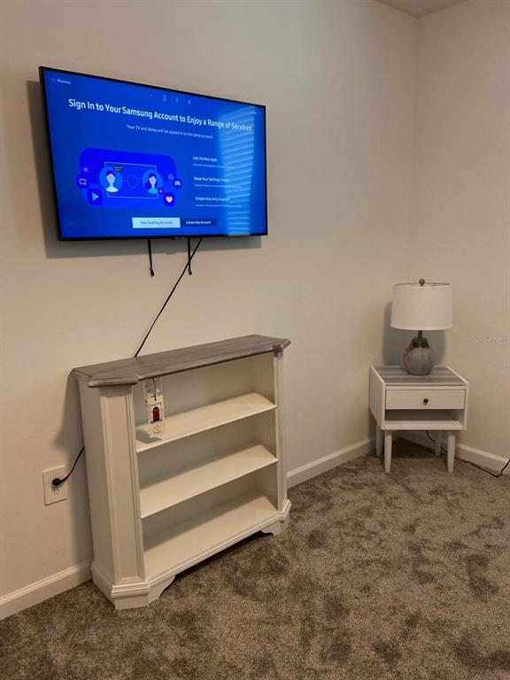 A bedroom features a wall-mounted television, a white bookshelf, and a matching bedside table — 8863 CABOT CLIFFS DRIVE UNIT 102, DAVENPORT, FL