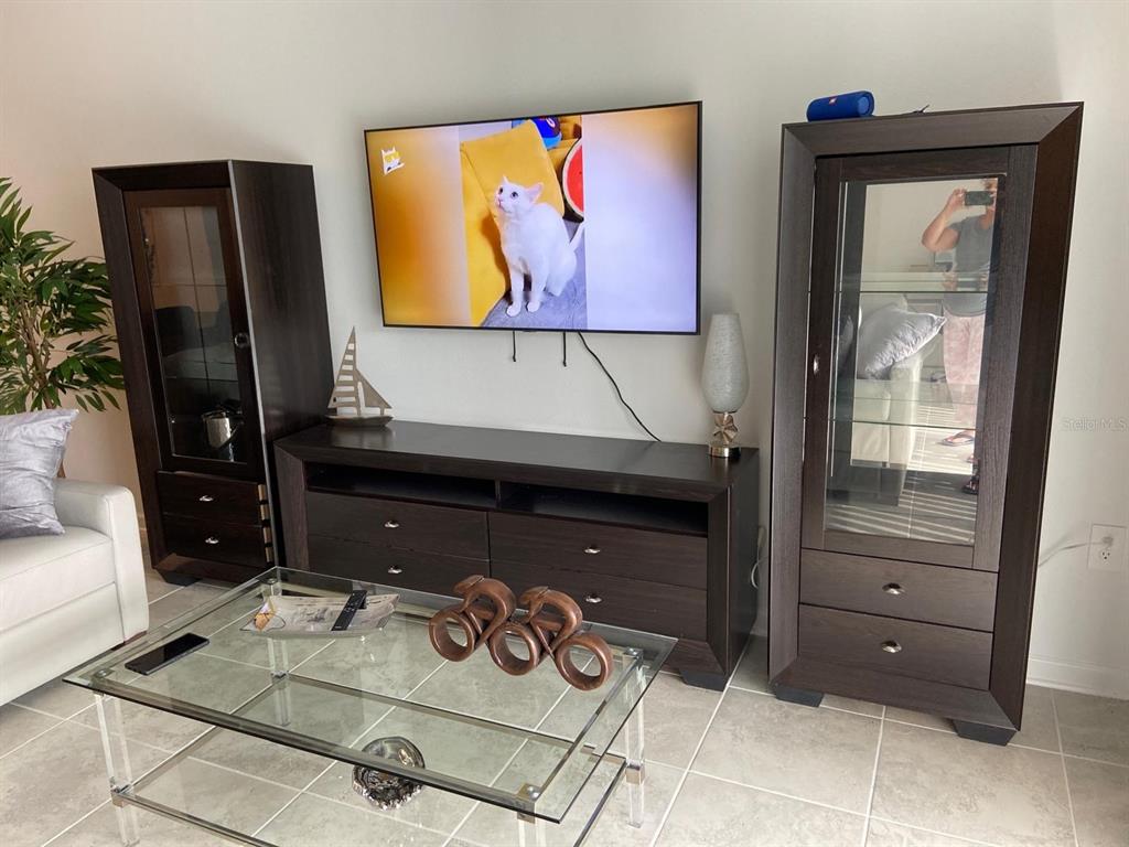 A living room with light gray sofas, a glass coffee table, and an adjacent kitchen — 8863 CABOT CLIFFS DRIVE UNIT 102, DAVENPORT, FL