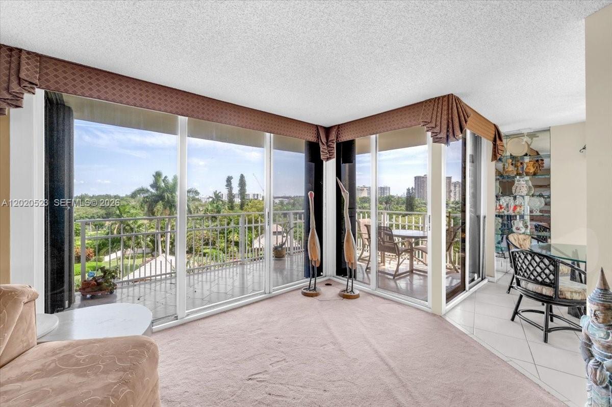 A carpeted living room features floor-to-ceiling glass sliding doors opening onto a balcony — 1000 Quayside Ter # 701, Miami FL 33138, MIAMI, FL