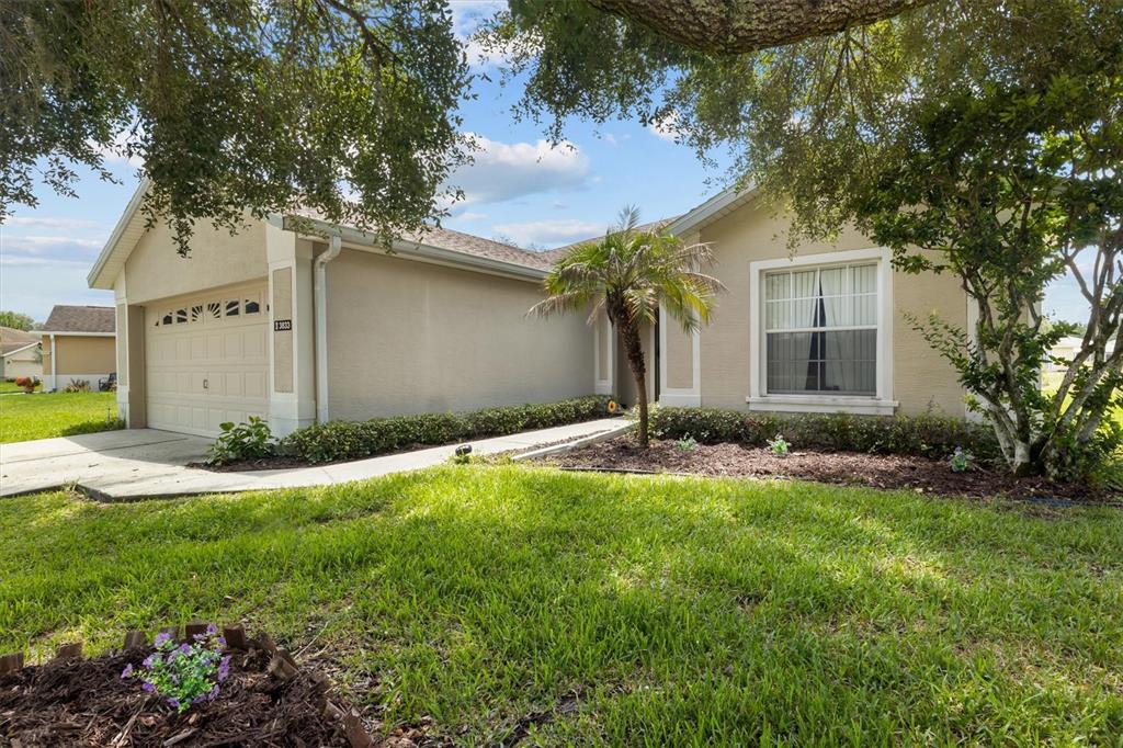 A single-story house with a beige stucco exterior, a two-car garage, and a front lawn — 3833 WHISTLEWOOD CIRCLE, LAKELAND, FL