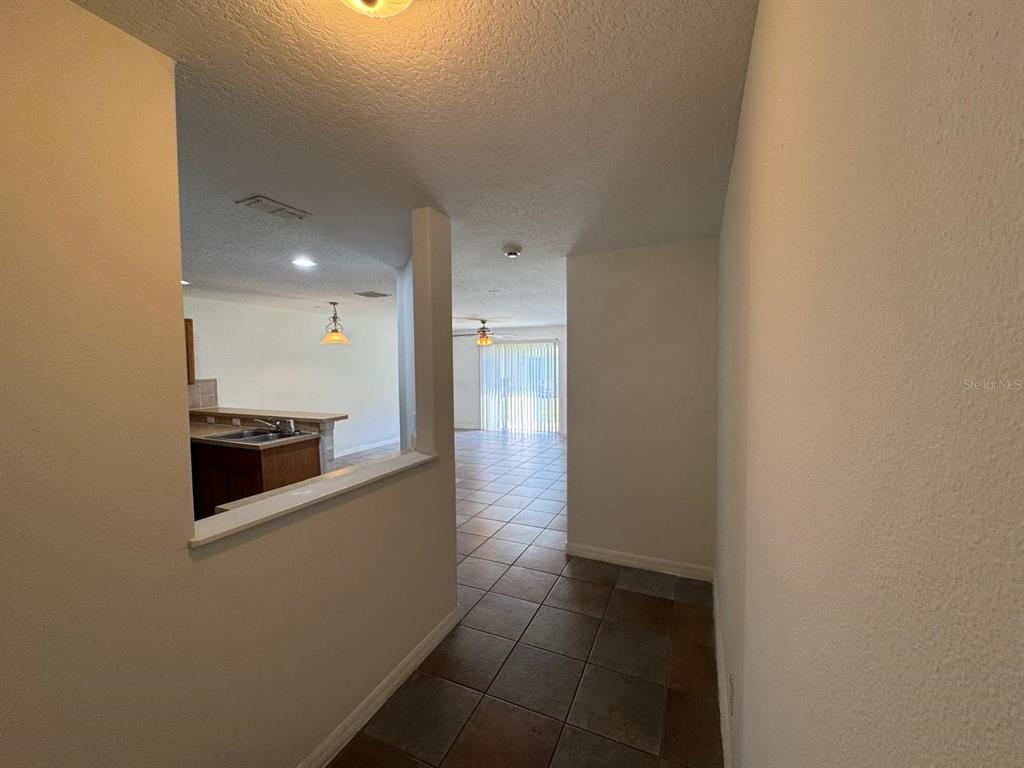 A tiled entryway leads to a kitchen with a pass-through window and a living area — 561 CRESTING OAK CIRCLE UNIT 86, ORLANDO, FL