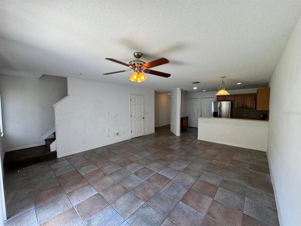 An open-concept living area features tiled floors, a ceiling fan, and an adjacent kitchen — 561 CRESTING OAK CIRCLE UNIT 86, ORLANDO, FL
