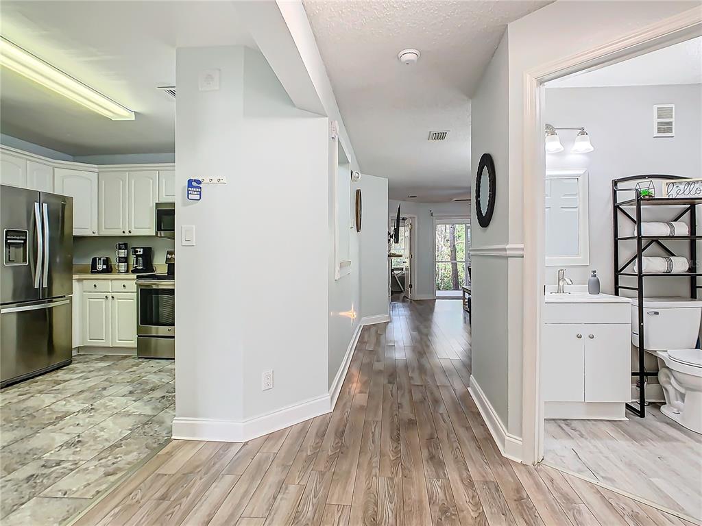 A view from a hallway looking into a kitchen on the left and a bathroom — 8825 CORAL PALMS COURT UNIT A, KISSIMMEE, FL
