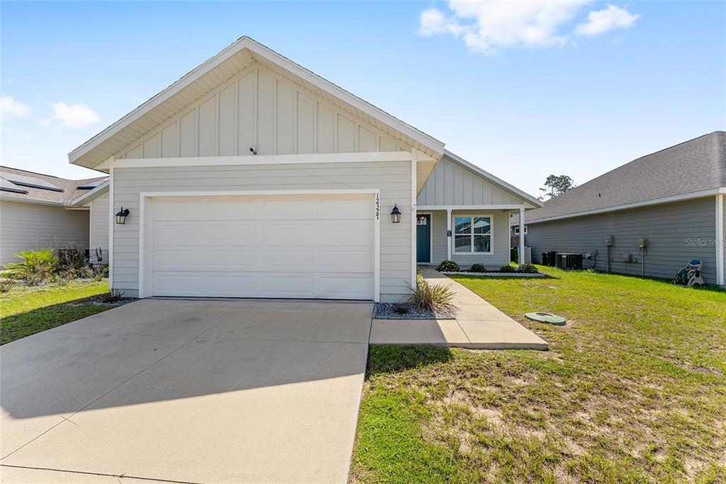 A light-colored single-story house with a two-car garage and a concrete driveway — 12327 NW 159TH WAY, ALACHUA, FL