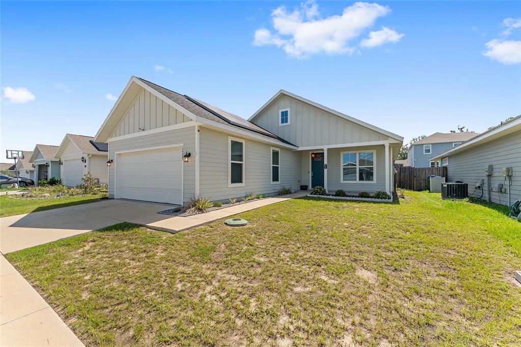 A light-colored single-story house with a two-car garage and a front walkway — 12327 NW 159TH WAY, ALACHUA, FL