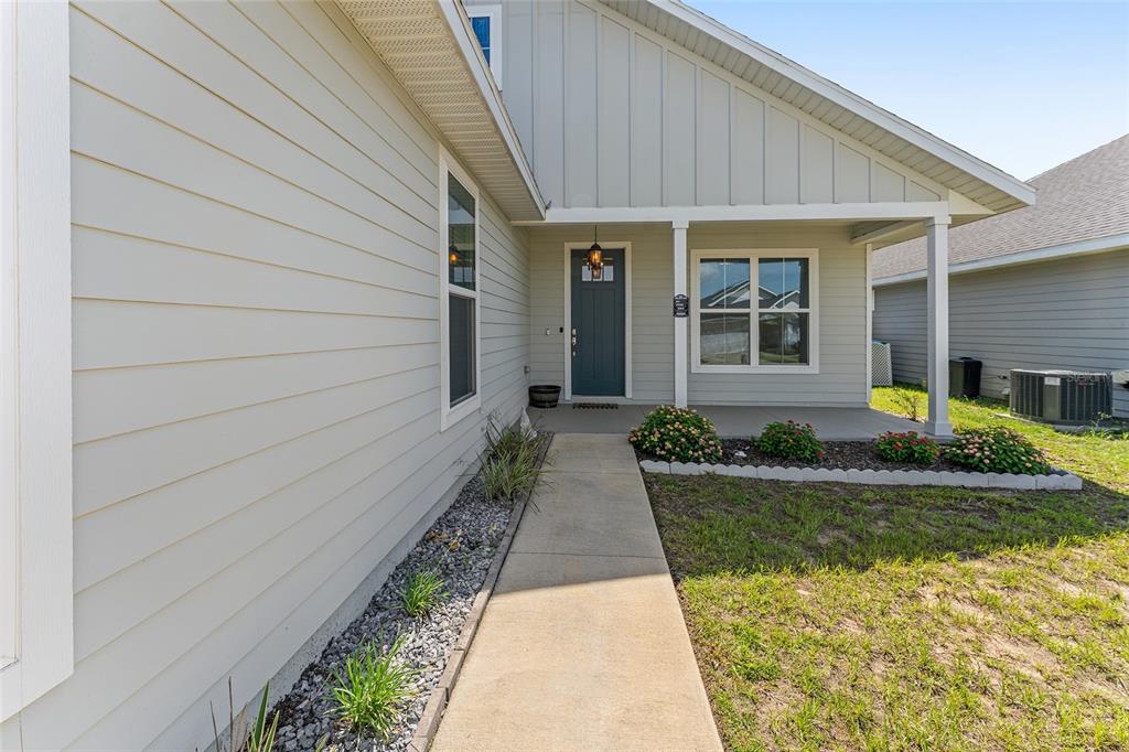 A light-colored house exterior features a concrete walkway leading to a dark blue front door — 12327 NW 159TH WAY, ALACHUA, FL