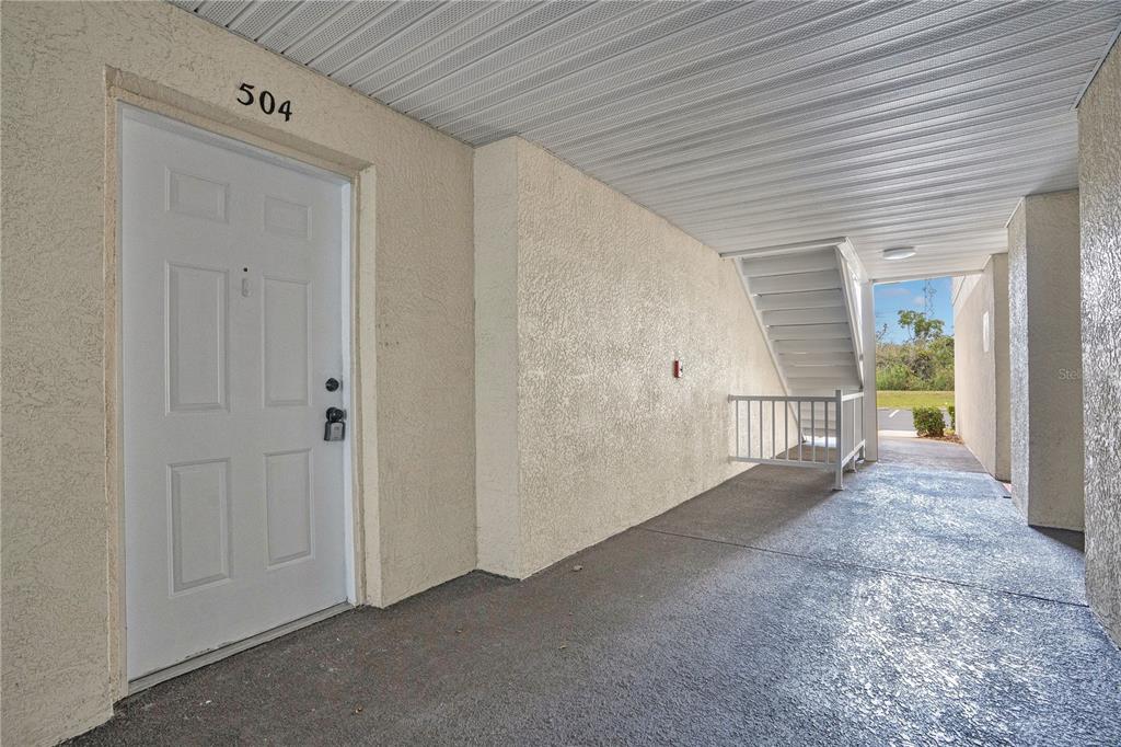 An exterior view of a building entrance with a white door labeled 504 and stairs — 3960 SOUTHPOINTE DRIVE UNIT 504, ORLANDO, FL