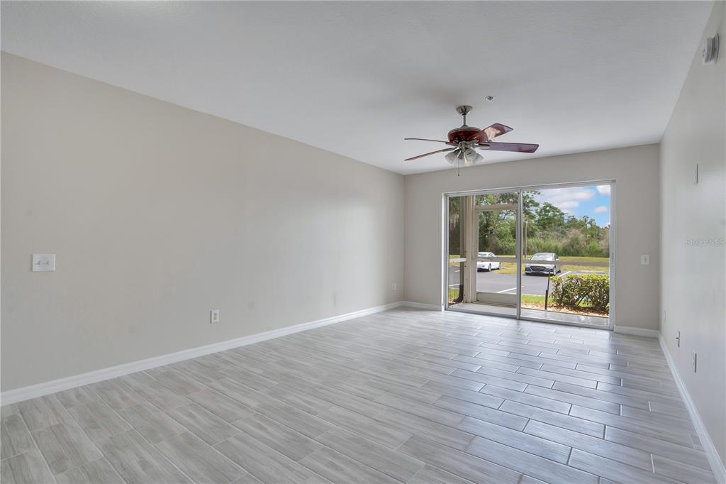 An empty room with light gray tile flooring, a ceiling fan, and a sliding glass door — 3960 SOUTHPOINTE DRIVE UNIT 504, ORLANDO, FL