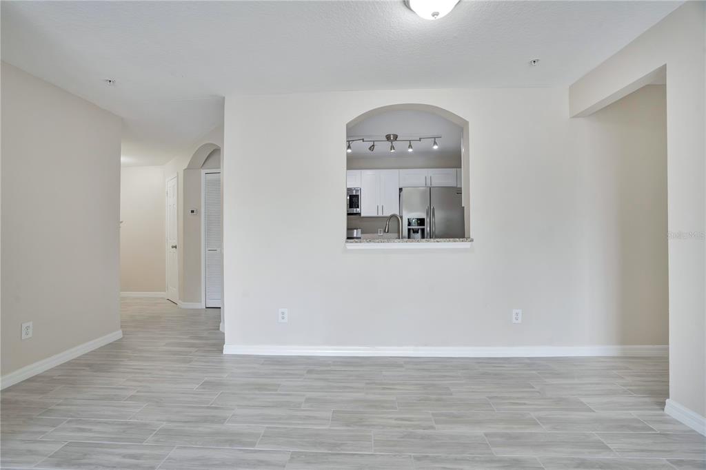 A living area with light wood-look tile flooring and a pass-through opening to the kitchen — 3960 SOUTHPOINTE DRIVE UNIT 504, ORLANDO, FL