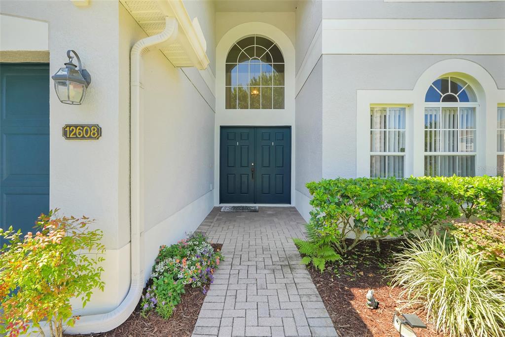 A paved walkway leads to the dark double front doors of a suburban home — 12608 WEATHERFORD WAY, ORLANDO, FL