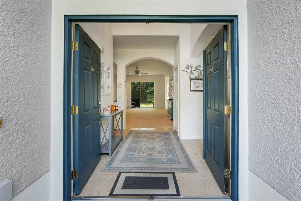 An open front door reveals a tiled entryway leading to a carpeted living area — 12608 WEATHERFORD WAY, ORLANDO, FL