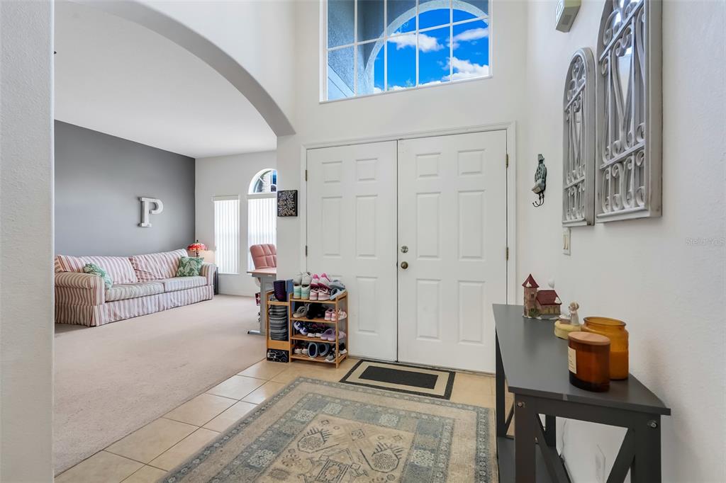A tiled entryway with a rug leads to a living room with a striped sofa — 12608 WEATHERFORD WAY, ORLANDO, FL