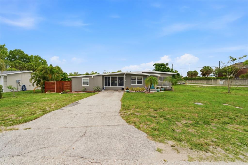 A single-story gray house with a concrete driveway and a small palm tree in front — 100 AVERY AVENUE, CRYSTAL BEACH, FL