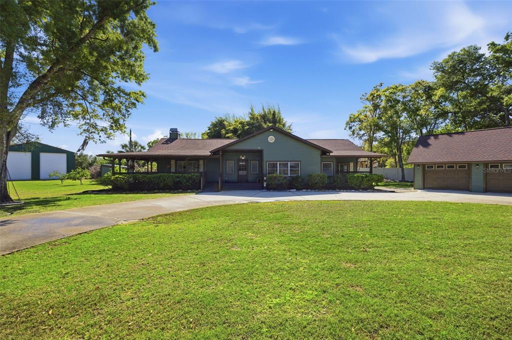 A green single-story house with a wraparound porch and a detached garage on a lawn — 3752 OLD KEYSTONE ROAD, TARPON SPRINGS, FL