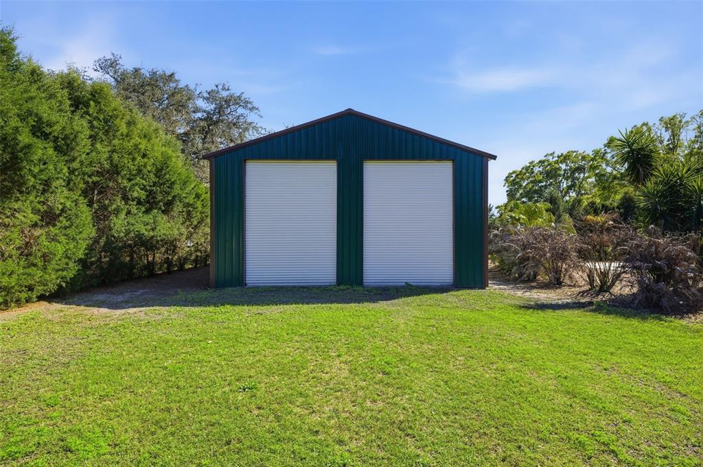 A detached metal garage with two roll-up doors stands on a grassy lot — 3752 OLD KEYSTONE ROAD, TARPON SPRINGS, FL