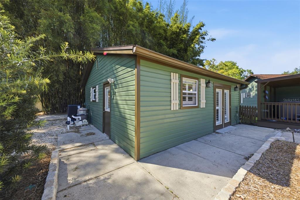 A green shed with a concrete patio and double doors stands next to a fence — 3752 OLD KEYSTONE ROAD, TARPON SPRINGS, FL