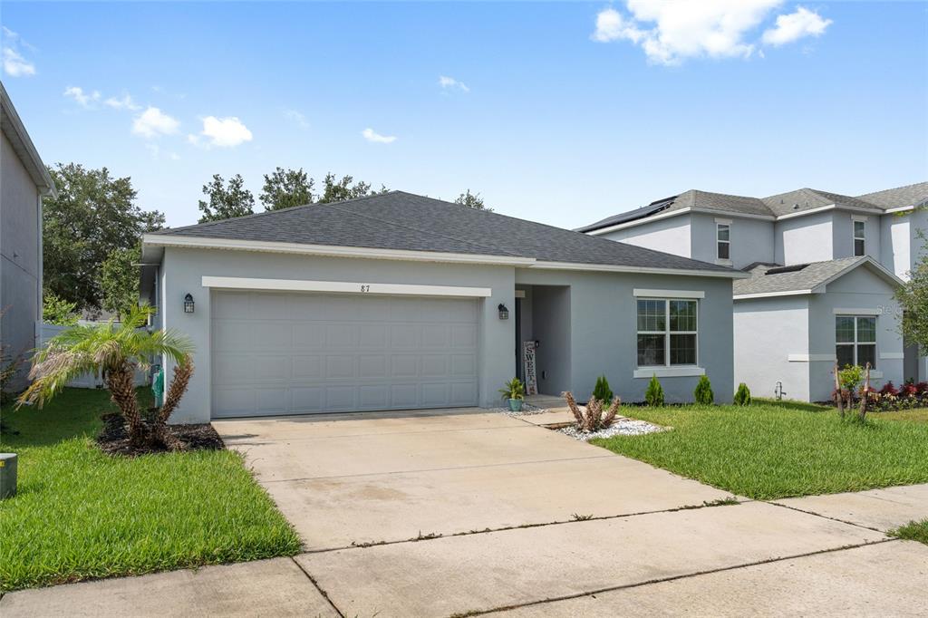 A single-story gray house with a two-car garage and a concrete driveway — 87 PRAIRIE FALCON DRIVE, GROVELAND, FL