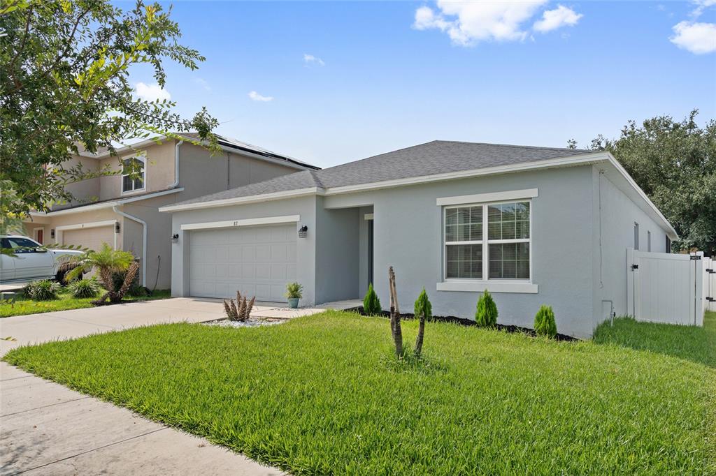 A single-story gray house with a two-car garage and a front lawn — 87 PRAIRIE FALCON DRIVE, GROVELAND, FL