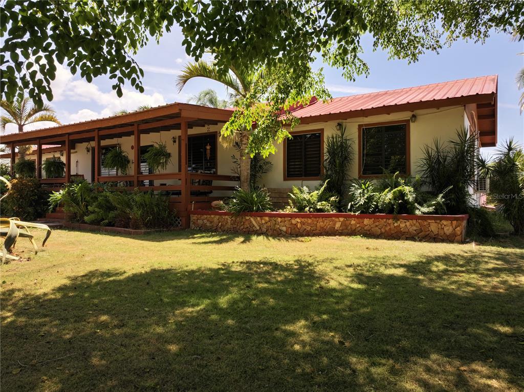 A single-story house with a red metal roof and a wooden front porch — SR 117 km 9.9 interior LA PLATA ST, LAJAS, PR
