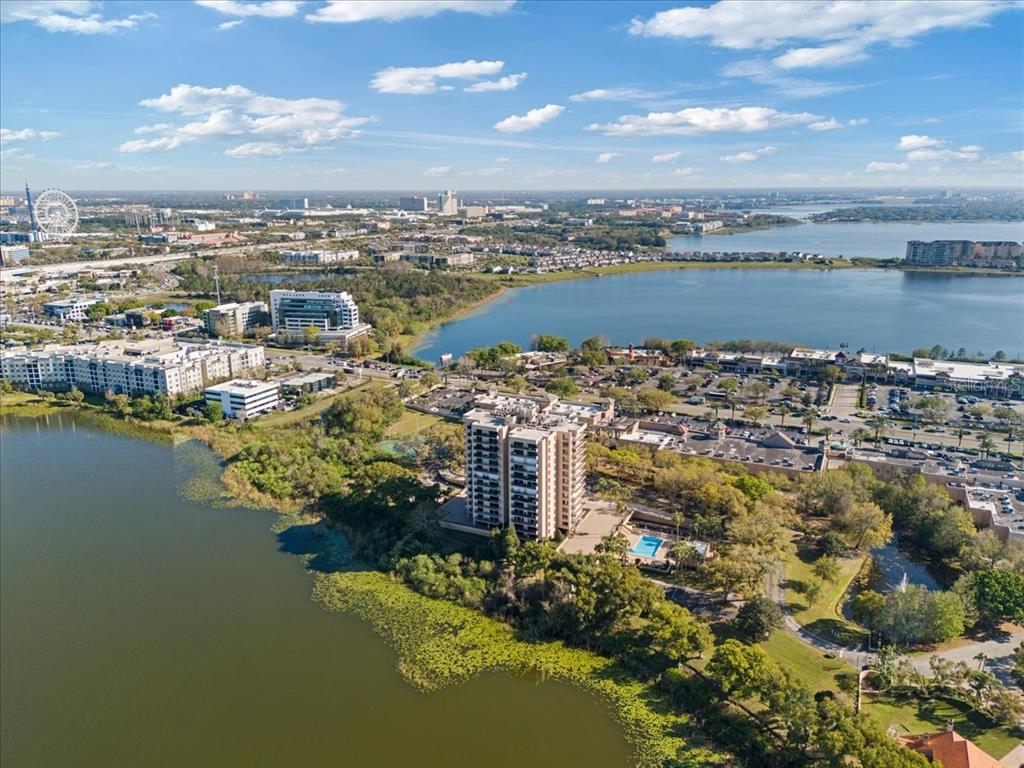 An aerial view shows a high-rise apartment building situated on a lakefront property — 7550 HINSON STREET UNIT 15D, ORLANDO, FL