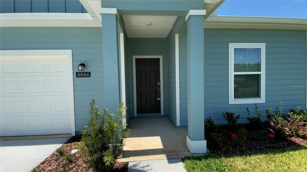 The exterior of a light blue house features a covered entryway and a garage — 4844 NW 11TH ST ROAD, OCALA, FL