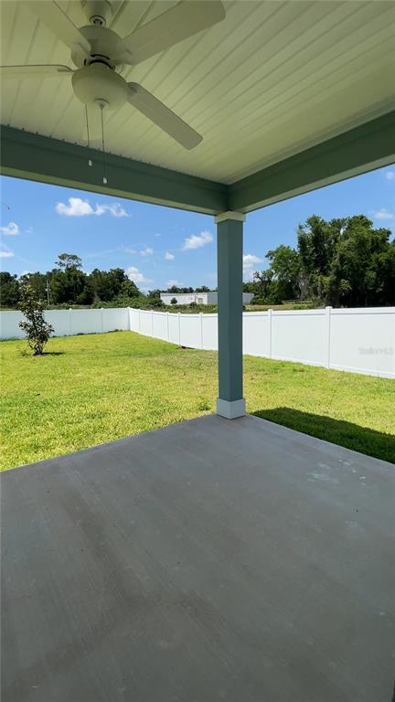 A covered concrete patio with a ceiling fan overlooks a fenced backyard — 4844 NW 11TH ST ROAD, OCALA, FL
