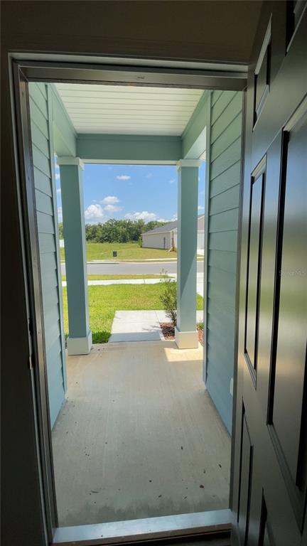 A view from an open doorway looking out onto a covered front porch and yard — 4844 NW 11TH ST ROAD, OCALA, FL