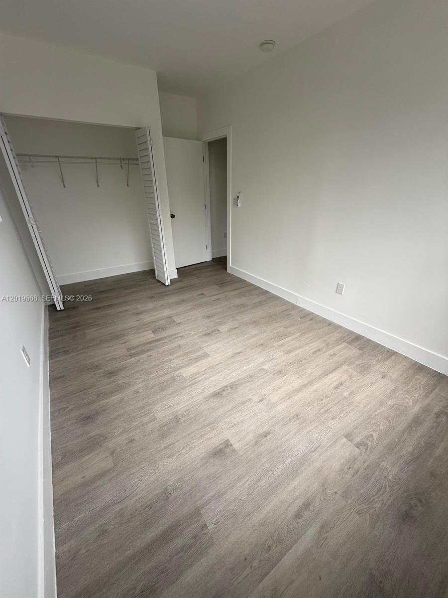 An empty bedroom features light wood-look flooring, white walls, and a closet with bifold doors — 2330 NW 9 St # 15, Miami FL 33125, MIAMI, FL