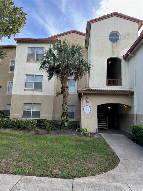 A three-story apartment building exterior features a palm tree, stucco walls, and a covered entrance — 827 CAMARGO WAY UNIT 307, ALTAMONTE SPRINGS, FL