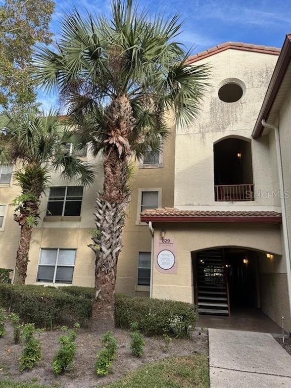 A three-story apartment building exterior features palm trees, a covered entrance, and a concrete walkway — 827 CAMARGO WAY UNIT 307, ALTAMONTE SPRINGS, FL