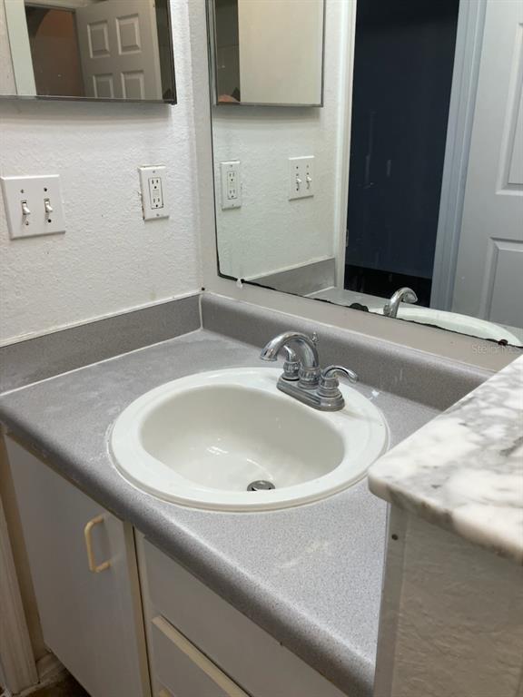 A bathroom vanity features a white drop-in sink, chrome faucet, and gray speckled countertop — 827 CAMARGO WAY UNIT 307, ALTAMONTE SPRINGS, FL