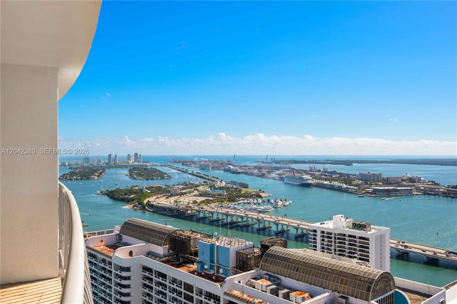 A high-angle view shows a balcony overlooking a bay with bridges, cruise ships, and buildings — 1750 N Bayshore Dr # 5212, Miami FL 33132, MIAMI, FL