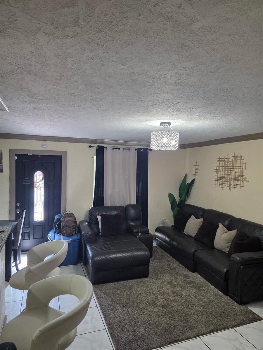 A living room features a dark leather sectional, a gray area rug, and white chairs — 621 SW 56th Avenue, Margate FL 33068, MARGATE, FL