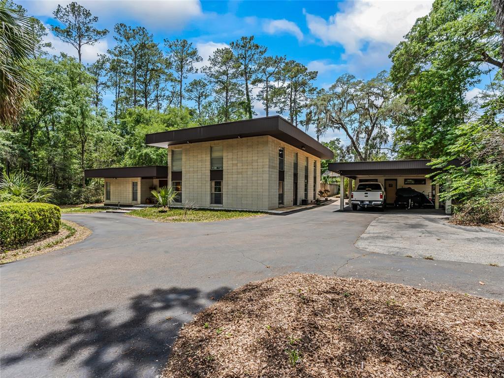 A two-story house with a flat roof and attached carport sits on a paved driveway — 2510 NW 30TH TERRACE, GAINESVILLE, FL