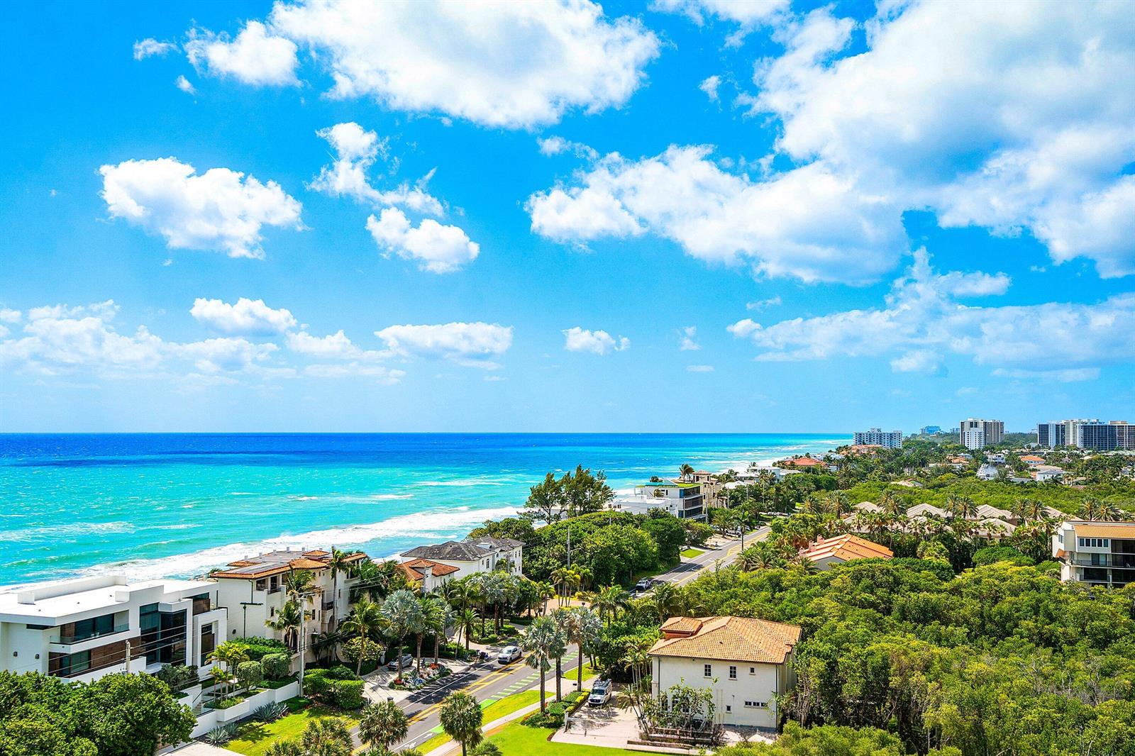 An aerial view of a coastal neighborhood featuring houses, lush trees, and the turquoise ocean — 3740 S Ocean Boulevard # 1102, Highland Beach FL 33487, HIGHLAND BEACH, FL