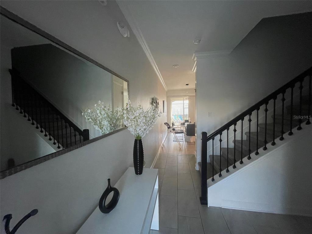 A bright entryway features a staircase with black railings, a mirror, and a console table — 4295 PARAGRAPH DRIVE, KISSIMMEE, FL