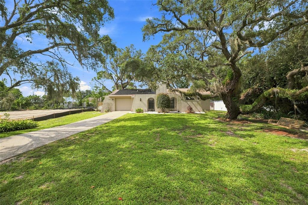 A single-story house with a garage and a large front yard under mature oak trees — 400 FAIRBANKS ROAD, SPRING HILL, FL