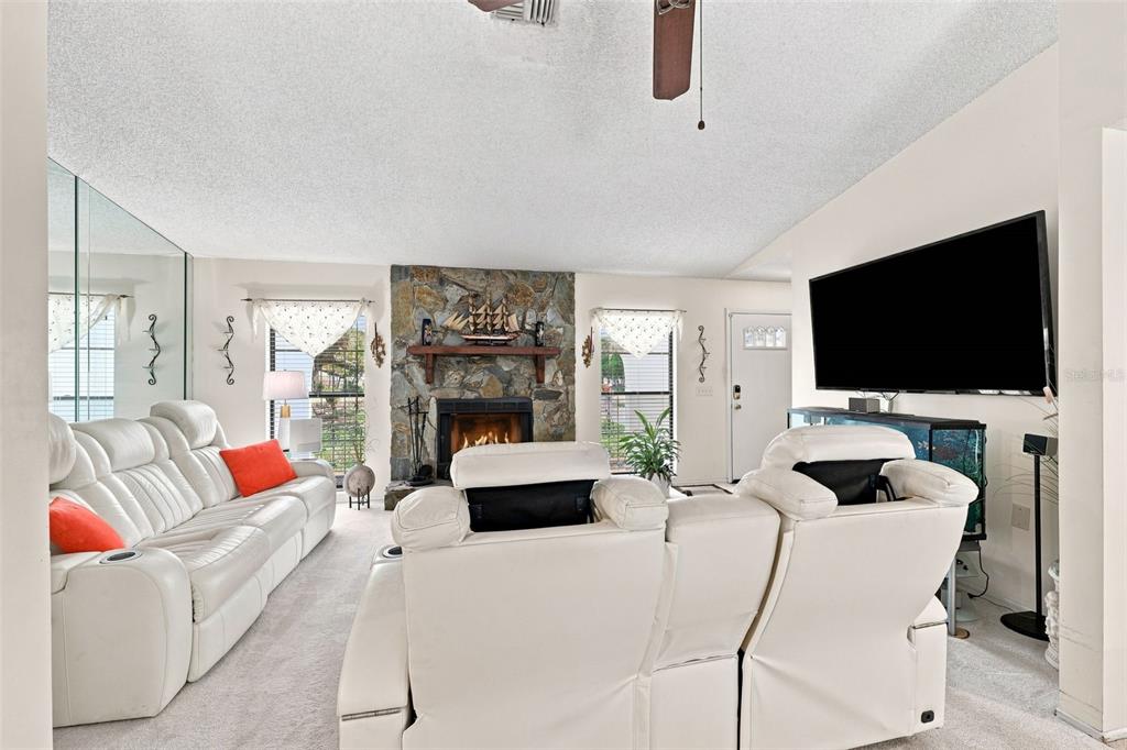 A living room features a stone fireplace, white leather sofas, and a large television — 400 FAIRBANKS ROAD, SPRING HILL, FL