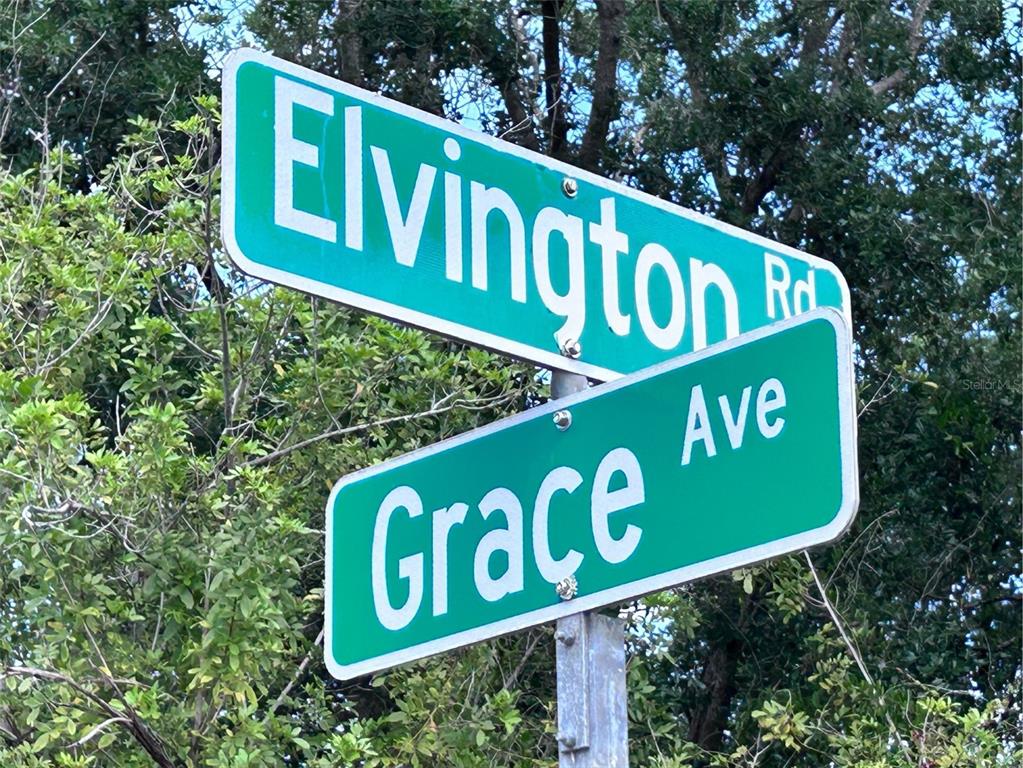 A street sign shows the intersection of Elvington Rd and Grace Ave against a leafy background — 12231 GRACE AVENUE, PORT CHARLOTTE, FL