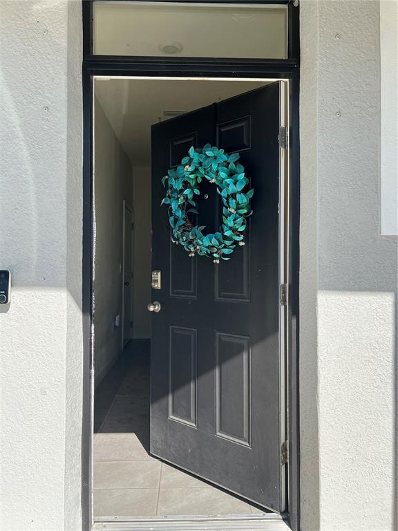 A black front door with a teal wreath opens into a tiled entryway — 184 MANGROVE SHADE CIRCLE, APOLLO BEACH, FL