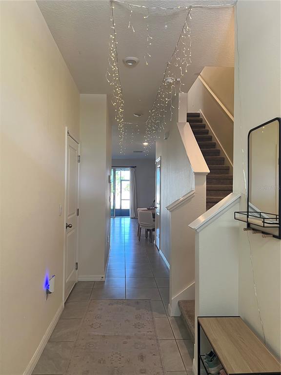 A tiled entryway features a staircase, a hallway leading to a living area, and string lights — 184 MANGROVE SHADE CIRCLE, APOLLO BEACH, FL