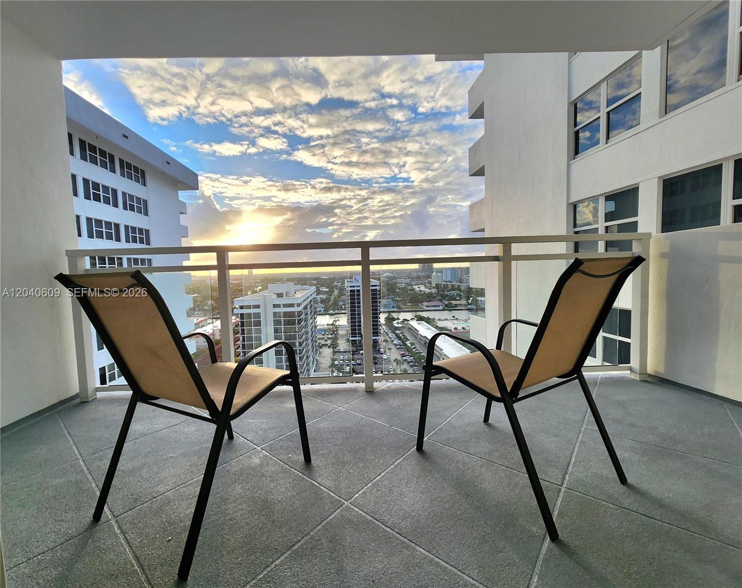 A balcony with two chairs overlooks a city skyline at sunset — 2030 S Ocean Dr # 1901, Hallandale Beach FL 33009, HALLANDALE BEACH, FL