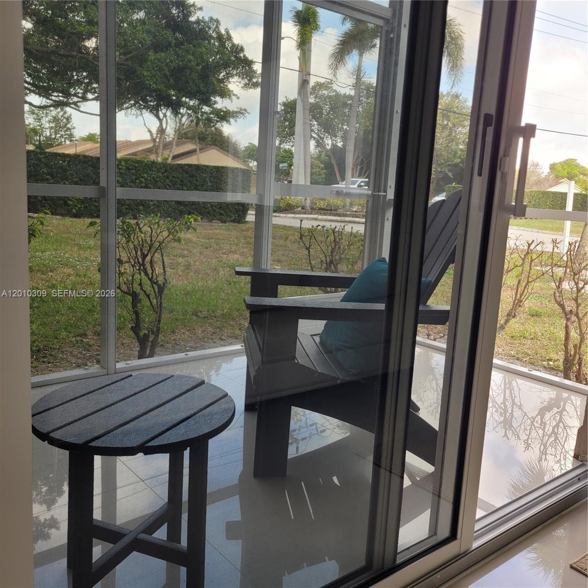A view through a sliding glass door of a screened patio with a chair and table — 8101 SW 24th Ct # 108, Davie FL 33324, DAVIE, FL