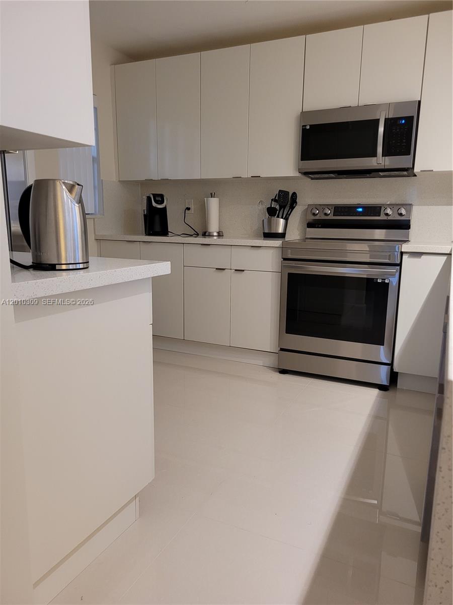 A modern kitchen features white cabinets, stainless steel appliances, and light-colored countertops — 8101 SW 24th Ct # 108, Davie FL 33324, DAVIE, FL